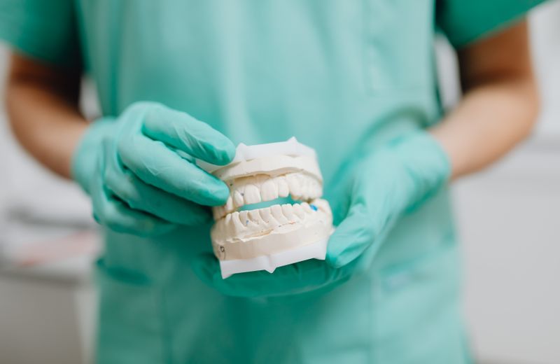 Dental technician holding a plaster cast of upper and lower dentures